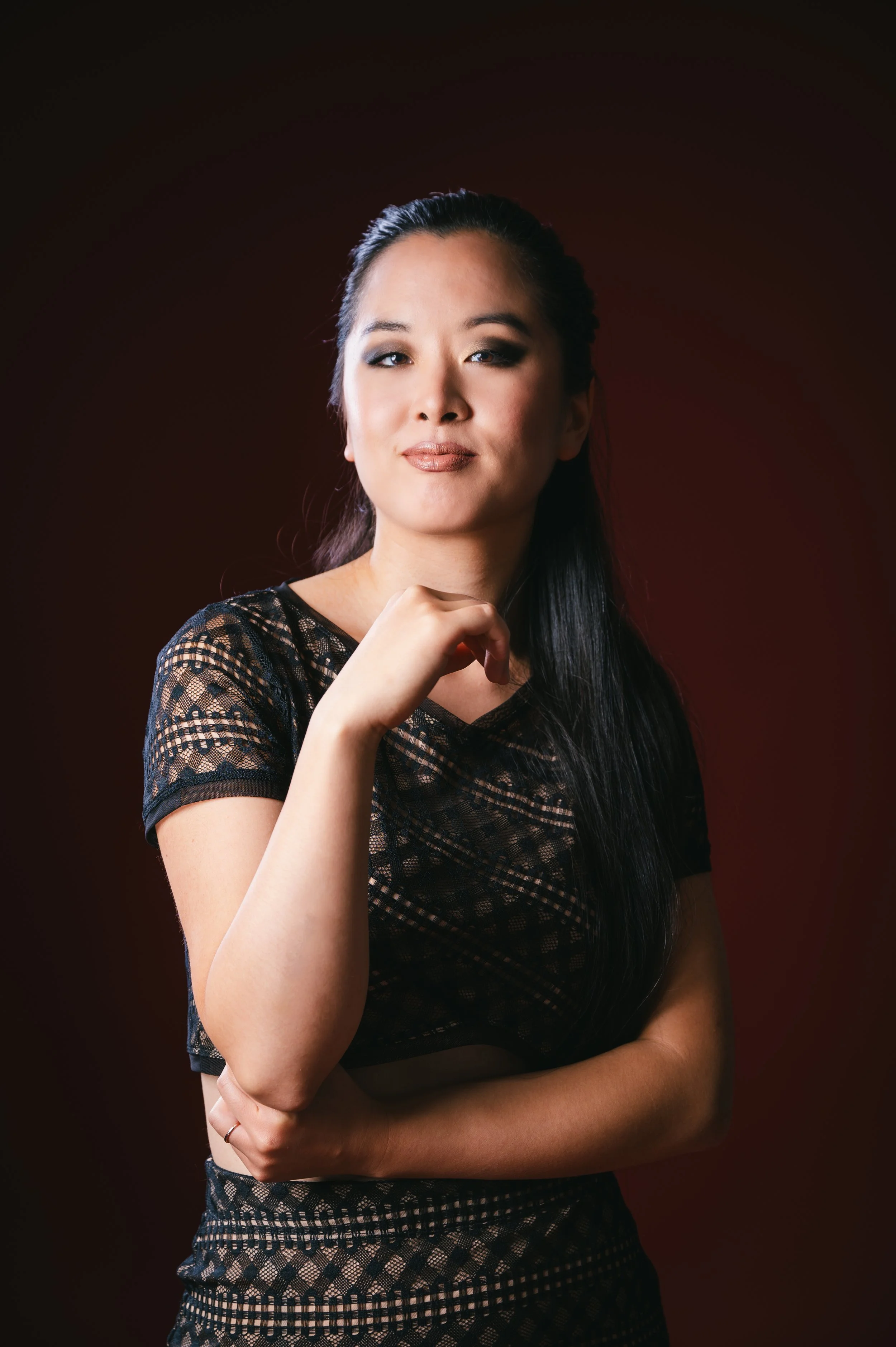 Fiona Wu in a black lace dress, photographed against a warm, dark studio backdrop